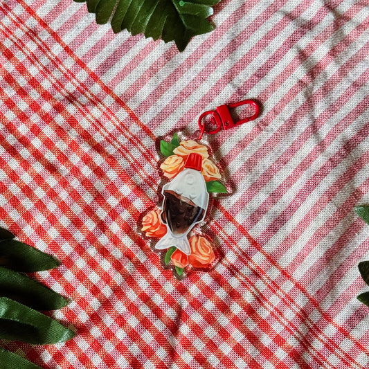Floral keychain on a red and white checkered fabric with leaves around