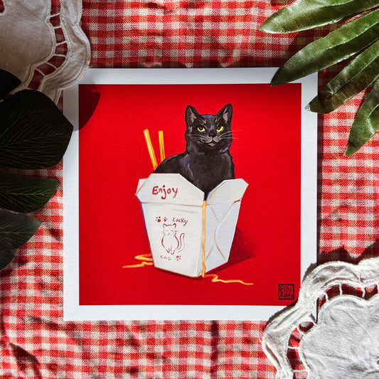 Framed artwork of a black cat in a Chinese takeout box on a red background with a checkered tablecloth.